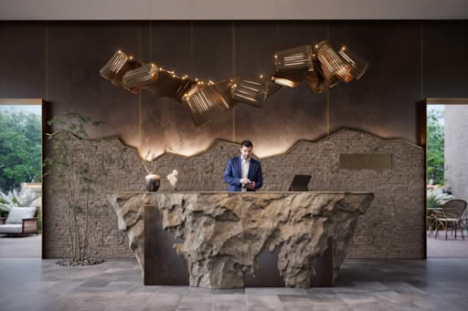 A modern reception desk with a unique rock-like design and elegant lighting above.